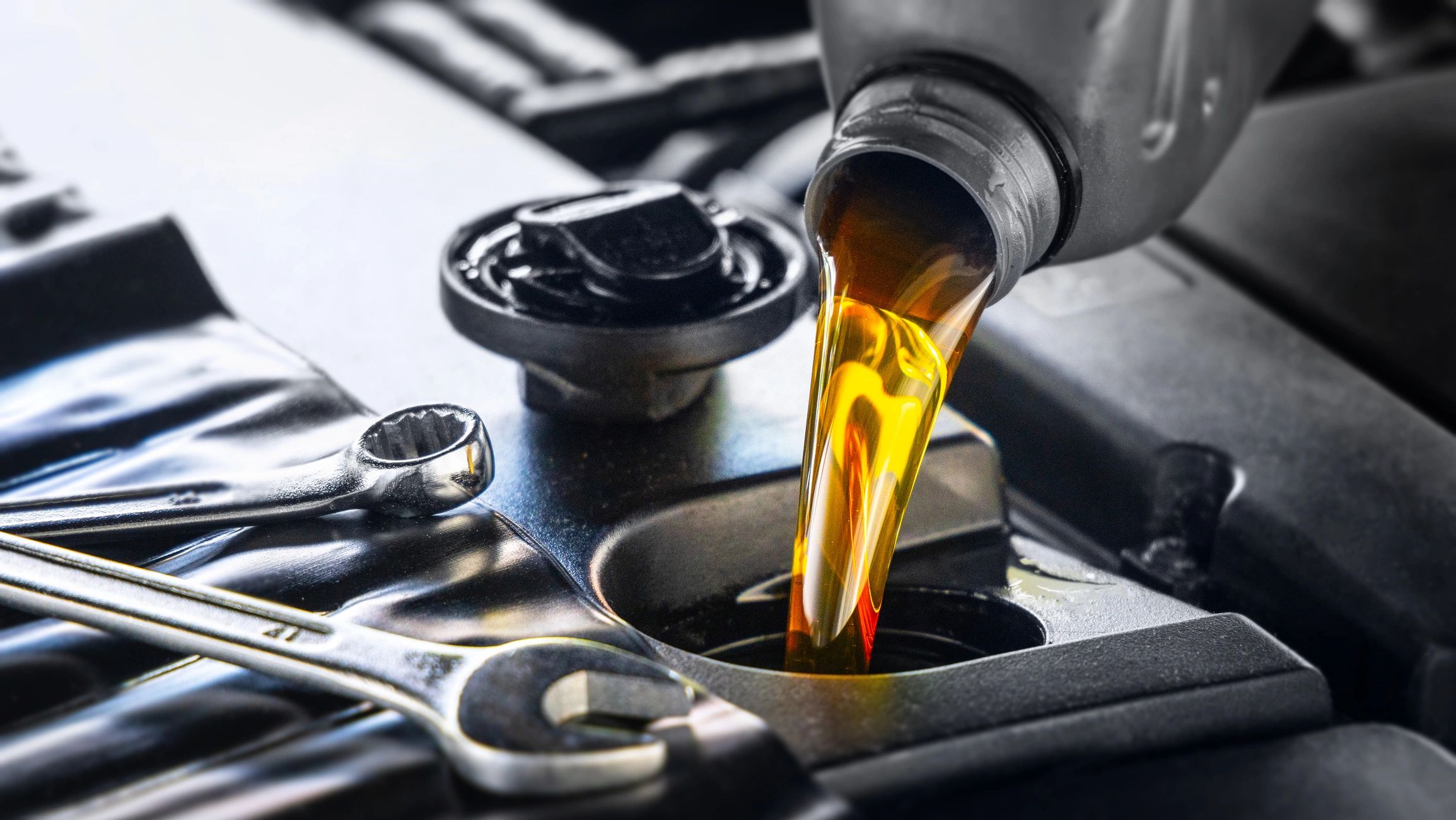 Technician performing fluid service in a vehicle engine bay