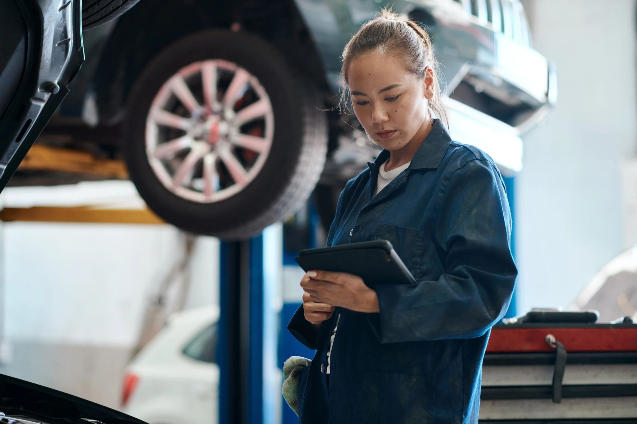 Mechanic holding a tablet while performing a vehicle system check