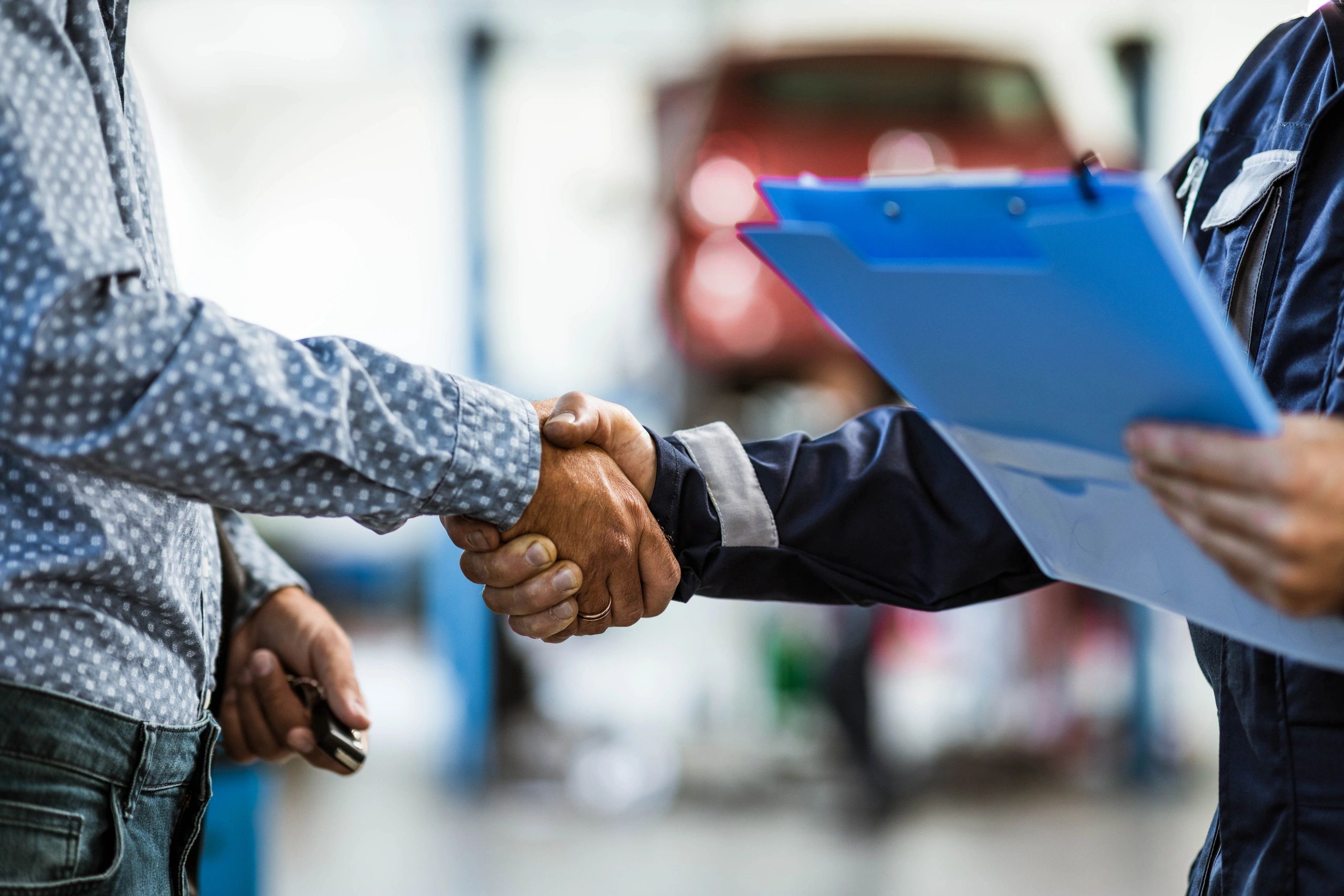 Close-up handshake between mechanic and customer in an auto repair shop